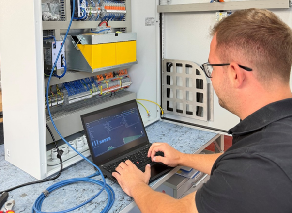 Techniker arbeitet mit Laptop an einem Schaltschrank für Monitoring und Systemintegration